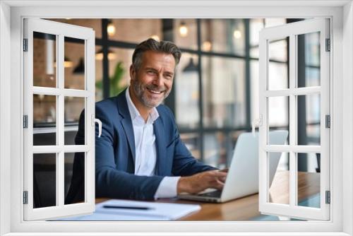 Smiling elegant handsome mid aged business man executive sitting at desk using laptop. Professional businessman worker or manager working on computer technology in modern office, Generative AI