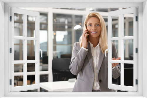 Smiling woman talking on smartphone in office, space for text. Lawyer, businesswoman, accountant or manager