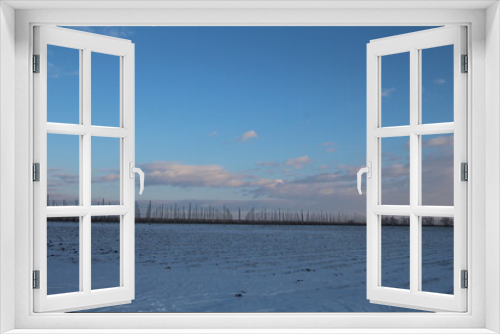 Fototapeta Naklejka Na Ścianę Okno 3D - A snowy field with a fence and blue sky