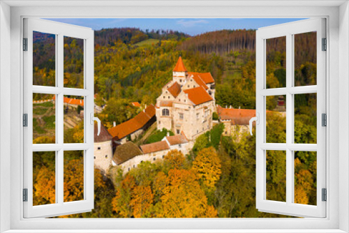 Picturesque autumn landscape with imposing historic Pernstejn Castle on rock above village of Nedvedice, Czech Republic