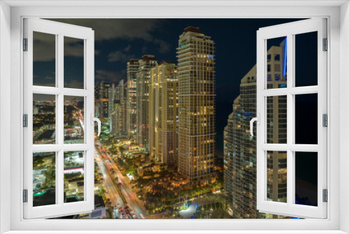 Fototapeta Naklejka Na Ścianę Okno 3D - View from above of brightly illuminated city street with dense traffic and high skyscraper buildings in downtown of Sunny Isles Beach in Florida, USA. American tourist urban district at night