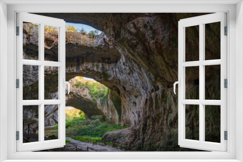 Fototapeta Naklejka Na Ścianę Okno 3D - Giant cave with big holes in the sealing, all full of trees and water - Devetashka cave