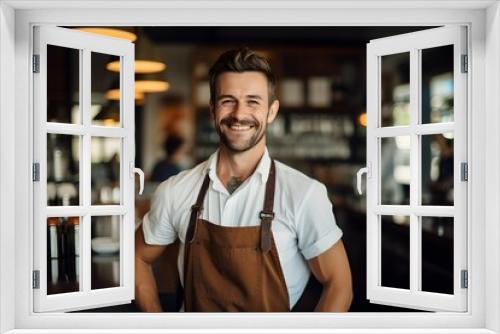 Stylish male barista in an apron standing confidently in a coffee shop