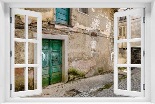 Fototapeta Naklejka Na Ścianę Okno 3D - Vintage green front door facing on an alley of an almost abandoned Italian mountain village. Canalaz, Grimacco, Udine province, Friuli Venezia Giulia, Italy. Urbex photography.