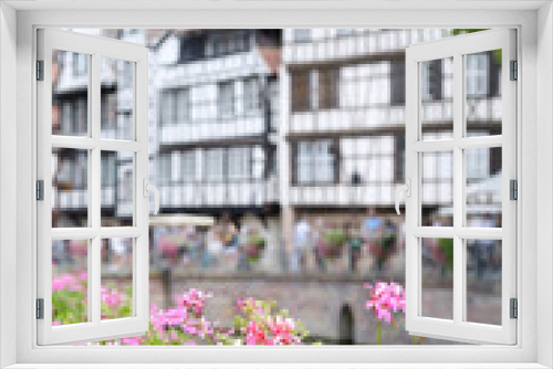 Fototapeta Naklejka Na Ścianę Okno 3D - In the foreground some pink flowers, in the background (out of focus) traditional half timbered houses, Strasbourg, Alsace, France.