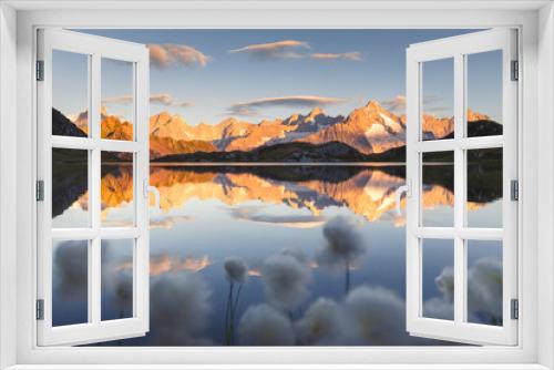 Fototapeta Naklejka Na Ścianę Okno 3D - Summer landscape view of a mountain range reflecting in a lake at sunrise, with cottongrass flowers in the foreground