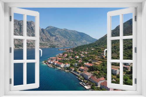 Fototapeta Naklejka Na Ścianę Okno 3D - Bird's eye view of a charming village of Prcanj along the azure waters of Kotor Bay, encircled by the lush mountains of Montenegro.