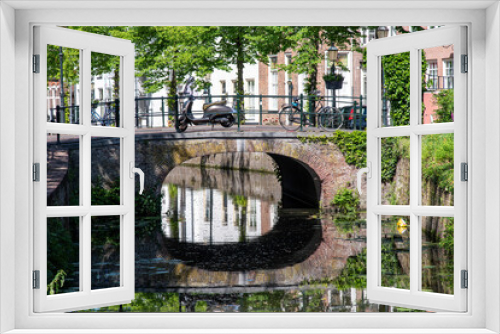Fototapeta Naklejka Na Ścianę Okno 3D - Close up view of bridge and street on Havik canal in Amersfoort, the Netherlands, lined with historic buildings and scooter and bicycles parked on bridge