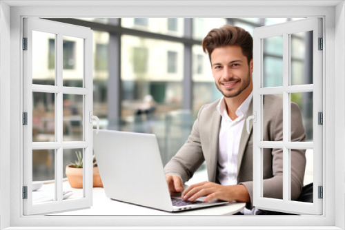 Handsome young businessman working with laptop in office. Space for text