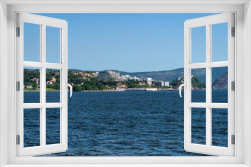 Fototapeta Naklejka Na Ścianę Okno 3D - Distant view of Niteroi's Sao Domingos and Gragoata districts coastline as saw from Guanabara bay blue waters under summer afternoon sunny clear blue sky.