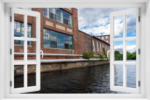 Fototapeta Naklejka Na Ścianę Okno 3D - Lowell, Massachusetts: Lowell National Historical Park celebrates era of textile manufacturing during the Industrial Revolution. Western Avenue on Pawtucket Canal, converted mill space.