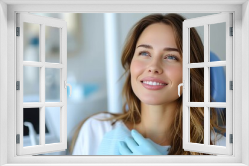 A beaming woman with blue gloves stands in front of a wall, her layered hair framing her joyful face as she shows off her stunning smile