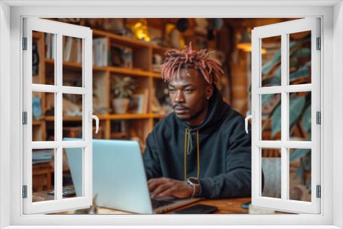 Serious young black businessman working on a laptop in a modern office, showcasing professionalism and dedication to his career.