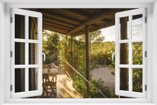 Fototapeta Naklejka Na Ścianę Okno 3D - Charming outdoor veranda with stylish furniture set amidst lush trees and shrubs in Portugal