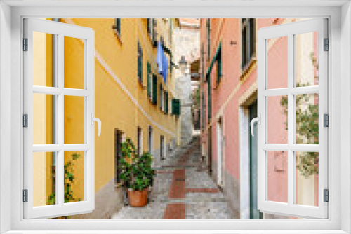 Fototapeta Naklejka Na Ścianę Okno 3D - Genoa, Italy. View of a very narrow alley in the small seaside village of Capolungo in Nervi. Characteristic houses with colorful walls. Vertical image. 2023-10-06.