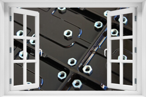 Steel nuts on a glossy plastic panel with rectangular compartments 
