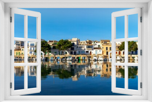 Fototapeta Naklejka Na Ścianę Okno 3D - panorama cityscape view of Portocolom with colourful and whitewashed houses and boat garages on the waterfront with reflections