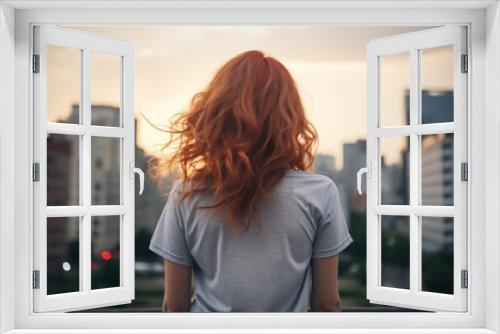 Young red-haired girl looking at the city, view from the back