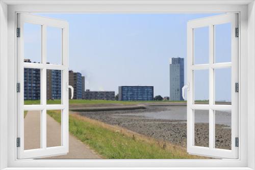 Fototapeta Naklejka Na Ścianę Okno 3D - the boulevard of the port city Terneuzen with flats and a residential tower behind the seawall of the westerschelde sea