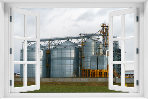 Fototapeta Naklejka Na Ścianę Okno 3D - silver silos on agro manufacturing plant for processing drying cleaning and storage of agricultural products, flour, cereals and grain. Large iron barrels of grain. Granary elevator