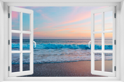 Fototapeta Naklejka Na Ścianę Okno 3D - The sun sets over the tranquil beach, casting warm hues across the sky and reflecting its pink and golden glow on the waves