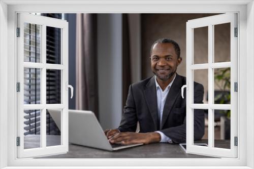 Professional african american businessman smiling at camera with laptop