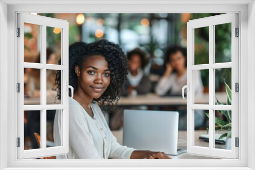 A woman with curly hair is sitting at a table with a laptop in front of her