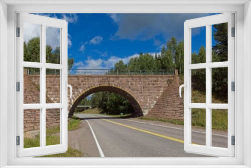 Fototapeta Naklejka Na Ścianę Okno 3D - Old arch bridge made of stone over Turuntie road in summer with clouds in the sky, Myllylampi, Nummela, Finland.