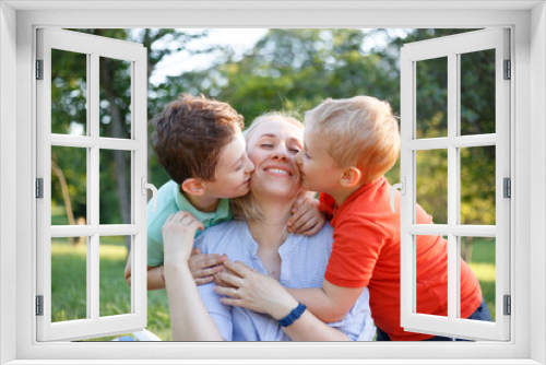 Mother with her kids they are together at a picnic, they hug each other. Outside portrait.