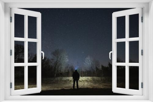 Fototapeta Naklejka Na Ścianę Okno 3D - Night scene, landscape astrophoto, Estonian nature. A man with a headlamp in a field.