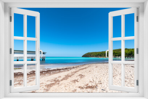 Fototapeta Naklejka Na Ścianę Okno 3D - Resort location of white sand beach and turquoise waters of a bay in Antigua and Barbuda with a white dock in the water