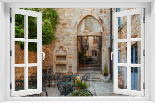 Fototapeta Naklejka Na Ścianę Okno 3D - Cafe tables and chairs outside in old cozy street in the in old medieval town Hvar in outdoor restaurant with nobody, Dalmatia, Croatia. Vertical orientation. Popular travel and tourist destination