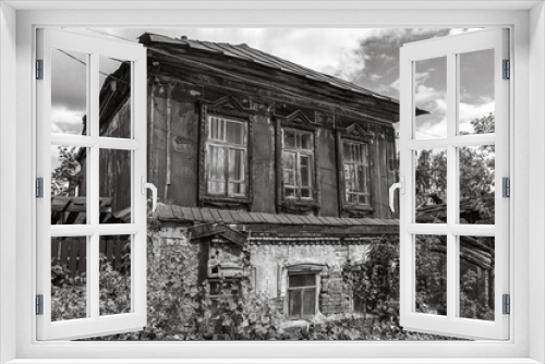 Fototapeta Naklejka Na Ścianę Okno 3D - The plaster is peeling off the brick on the old house. A dilapidated house built in the 19th century. The second wooden floor of the old house is covered with iron, which is covered with rust.