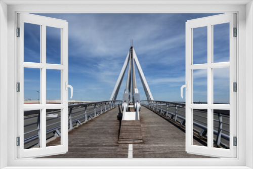 Fototapeta Naklejka Na Ścianę Okno 3D - Bridge with wooden pedestrian walkway floor with paint marks and metal braces to support the structure on a day with blue skies