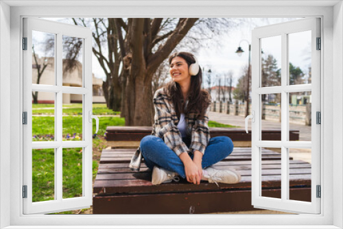 One young girl or woman is listening to music on her wireless headphones and enjoying the sun outdoors	
