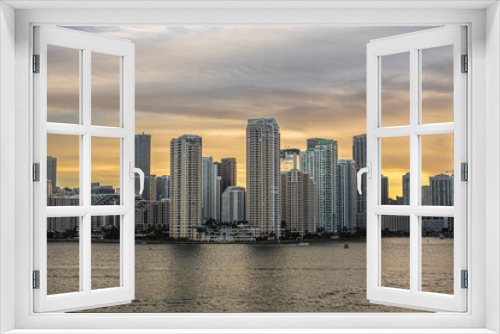 Fototapeta Naklejka Na Ścianę Okno 3D - Miami, Florida, USA - July 29, 2023: Gray to yellow colored sky over buildings on Brickell Key island at evening 19:47. Centinel statue between Tequesta points. River mouth on right 