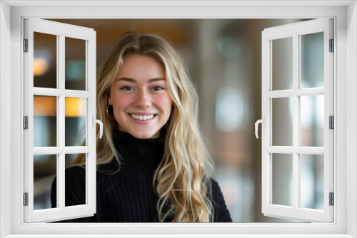 Adorable and lovely female, teenage student with blonde hair. The schoolgirl wearing a black sweater smiling in the school hallway