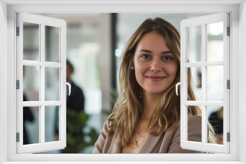 A contemporary real photo showcasing a smiling, attractive, confident professional young woman posing confidently in her office