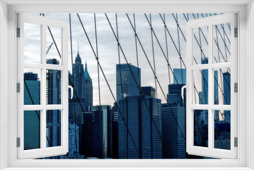Fototapeta Naklejka Na Ścianę Okno 3D - skyscrapers of New York. view through the grille of the Brooklyn Bridge. Minimalism in gray and blue tones.