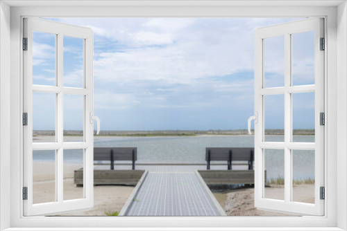 Fototapeta Naklejka Na Ścianę Okno 3D - A viewing platform with benches at a marsh with open water and clouds. 