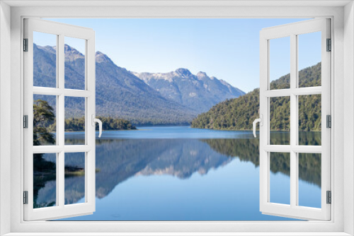 Fototapeta Naklejka Na Ścianę Okno 3D - Calm and relaxing horizontal view of mountain range full of dense forests reflecting onto a lake's crystaline tranquil water wallpaper