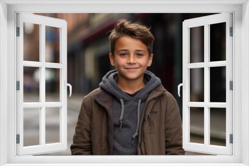 A young boy wearing a brown jacket and a gray hoodie is smiling