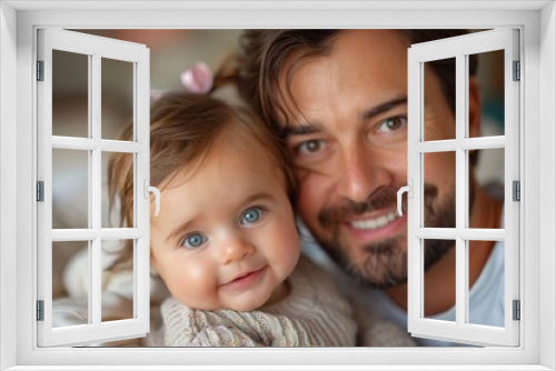 A close-up image of a father smiling with his baby girl who has big blue eyes and a cute expression