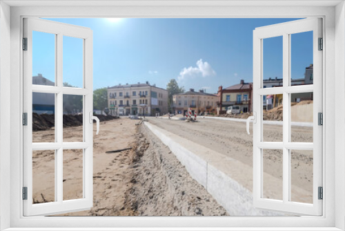 Fototapeta Naklejka Na Ścianę Okno 3D - Budowa dróg w Ostrowcu pod błękitnym niebem w południe we wrześniu. Granitowe krawężniki na drodze  w budowie. Chaos budowlany w centrum miasta.