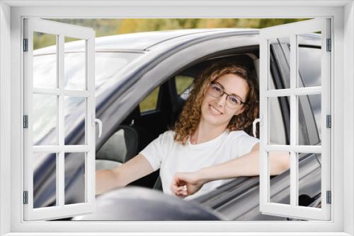 young beautiful smiling woman in car looking straight to camera, attractive caucasian woman in white t-shirt