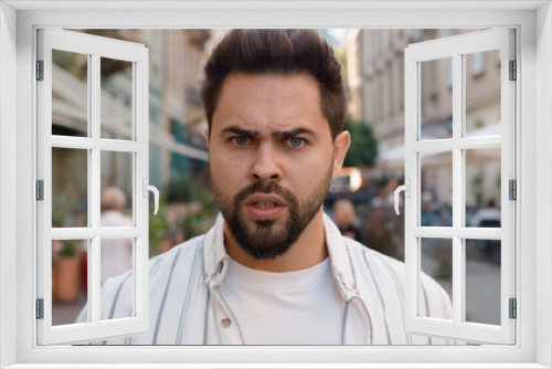 Close up angry Caucasian man frowning eyebrows city street outside dissatisfied displeased disappointed male problem trouble conflict emotion serious anger feeling frustrated guy hard negative annoyed