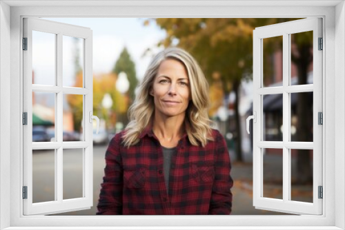 Portrait of a glad woman in her 40s dressed in a relaxed flannel shirt isolated in charming small town main street