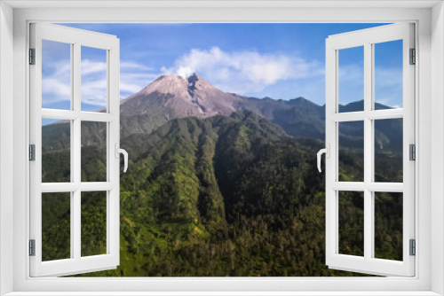 Aerial view of Merapi Volcano mountain covered by mist and fog in the morning with forest and hills below in Cangkringan, Sleman, Yogyakarta, Indonesia.