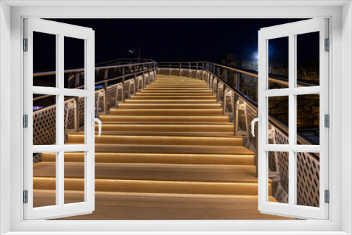 Fototapeta Naklejka Na Ścianę Okno 3D - The staircase is illuminated at night. Evening lighting of pedestrian bridges. Lanterns at night. The light of the lanterns illuminates the stairs. Twilight in the city.