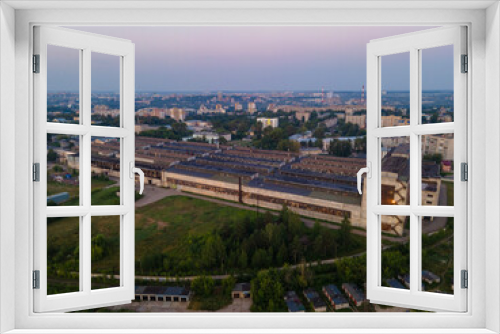 Fototapeta Naklejka Na Ścianę Okno 3D - Drone view of production building in small city at sunset